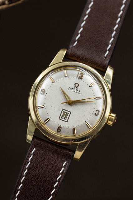 Montre Omega en or posée sur un bracelet cuir